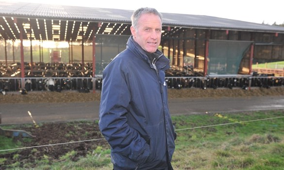 Dairy farmer stood in front of cow shed